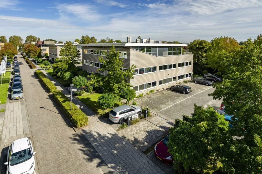 Kantoorgebouw aan de Jan Leentvaarlaan met parkeerplaatsen en omliggend groen op een zonnige dag.